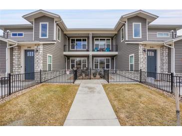 Charming exterior view of a two-story townhome with a balcony and fenced front yard with walkway at 330 High Point Dr # B102, Longmont, CO 80504