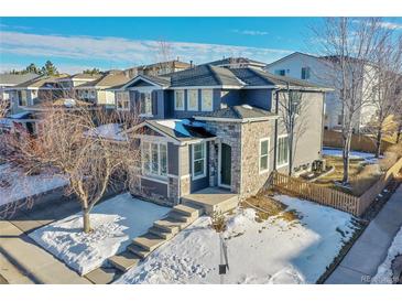 Two-story house with gray siding, stone accents, and a snow-covered yard at 10551 Applebrook Cir, Highlands Ranch, CO 80130