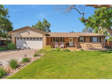 Charming brick home with a well-manicured lawn, cozy front porch with chairs, and a two car garage at 8262 Otis Ct, Arvada, CO 80003