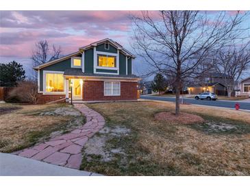 Charming two-story home featuring a brick facade, green siding, and a welcoming stone pathway at 375 Aspenwood Ct, Lafayette, CO 80026