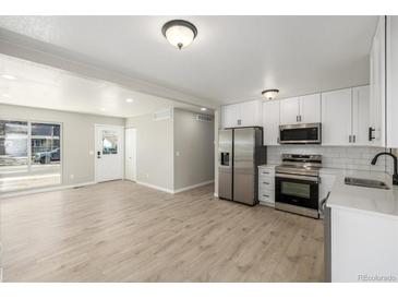 Bright kitchen features stainless steel appliances, white cabinetry, and new floors at 2260 S Lewiston St, Aurora, CO 80013