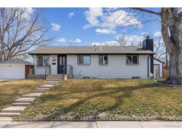 Charming ranch-style home with white brick exterior, black trim, and inviting front yard at 5060 S Fox St, Englewood, CO 80110