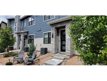 Charming two-story home featuring modern architectural design, stone accents, and a cozy front patio with seating at 9279 Merino Ct # B, Littleton, CO 80125