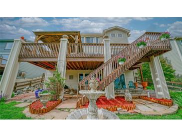 Charming backyard featuring a multi-tiered deck, fountain, and lush landscaping at 9832 N Crystal Lake Dr, Littleton, CO 80125