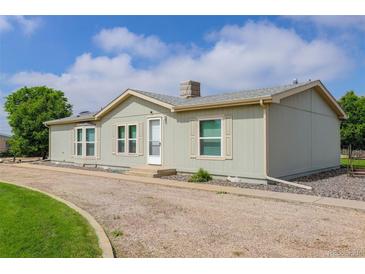 Charming single-story home featuring light green exterior, bright windows, and a gravel driveway at 8481 Uinta St, Commerce City, CO 80022