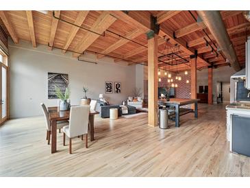 Bright, open living room with exposed wood beams, dining area, brick accent wall, and modern decor at 2955 Inca St # 2D, Denver, CO 80202