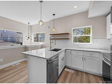 Modern kitchen showcasing white cabinets, quartz countertops, stainless steel appliances, and a stylish breakfast bar at 2140 S Ash St # 105, Denver, CO 80222