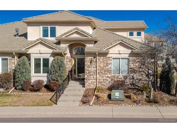 Inviting home entrance featuring stone accents, tiled roof, and manicured landscaping at 14033 E Whitaker Dr, Aurora, CO 80015