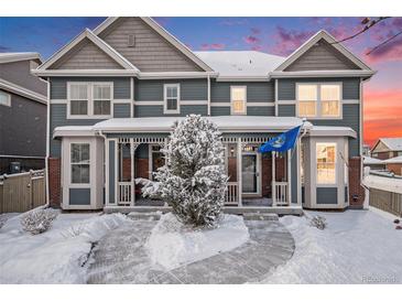 Charming townhome showcasing a snow covered yard, covered porch, and eye-catching blue siding with stone accents at 14693 E Crestridge Dr, Aurora, CO 80015