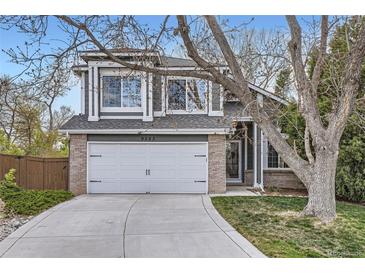 Charming home featuring a two-car garage, gray siding, brick accents and a well-maintained lawn at 9523 Sherrelwood Ln, Highlands Ranch, CO 80126