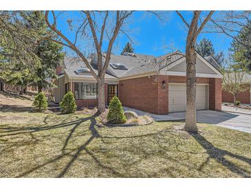 Charming brick home featuring mature trees, a well-manicured lawn, and an attached two-car garage at 8834 Blue Mountain Pl, Highlands Ranch, CO 80126