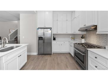 Bright kitchen with white cabinets, stainless steel appliances, gas range, and wood floors at 12214 Stone Timber Ct, Parker, CO 80134