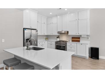 Bright kitchen features white cabinetry, stainless steel appliances, an island, and sleek countertops at 12214 Stone Timber Ct, Parker, CO 80134