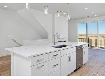 Bright white kitchen boasts stainless steel appliances, ample cabinet space, and an island with stone countertops at 10860 Lyric St, Lone Tree, CO 80134