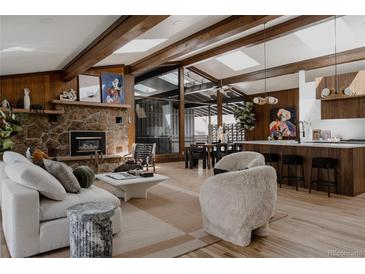 Spacious living room featuring a stone fireplace, wood paneling and exposed wood beams, plus modern decor at 2415 Urban St, Lakewood, CO 80215