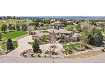 Stately stone and stucco home featuring a circular driveway and mature landscaping at 7390 Sagebrush Dr, Parker, CO 80138