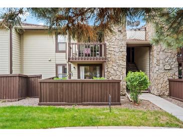 Inviting condo exterior with stone accents, second story balcony, and charming wood fence at 7710 W 87Th Dr # K, Arvada, CO 80005
