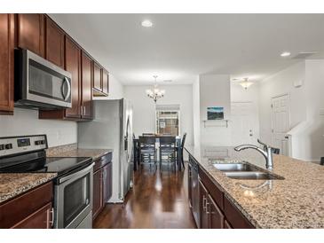 Modern kitchen with stainless steel appliances, granite counters, and dark wood cabinetry at 14700 E 104Th Ave # 805, Commerce City, CO 80022