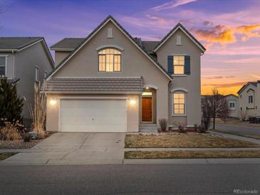 Charming two-story home featuring a two-car garage and a beautifully landscaped front yard at sunset at 15145 W Washburn Ave, Denver, CO 80228