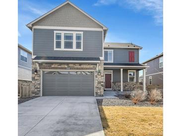 Charming two-story home featuring a stone facade, gray siding, covered porch, and a two-car garage at 20040 E 61St Dr, Aurora, CO 80019