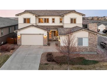 Inviting two-story home featuring a three-car garage, stone accents, and a well-manicured front yard at 11100 Pastel Pt, Parker, CO 80134