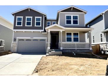 Charming two-story home featuring a covered porch, two-car garage, and a mix of gray and white siding at 25254 E Warren Pl, Aurora, CO 80018