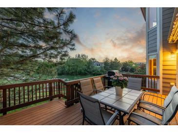 Enjoy outdoor dining on this spacious wood deck with a table and chairs overlooking a serene backyard at 5048 Rocky Mountain Dr, Castle Rock, CO 80109