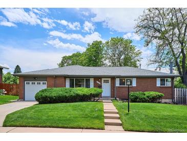 Charming brick home featuring a well-manicured lawn, mature landscaping, and an attached garage at 8490 E Davies Pl, Centennial, CO 80112