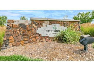 Stone monument sign at Turnberry community entrance with beautiful landscaping and blue skies at 13342 E 110Th Way, Commerce City, CO 80022