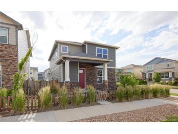Charming two-story home featuring a stone facade, red door, and attractive landscaping at 21854 E 9Th Pl, Aurora, CO 80018