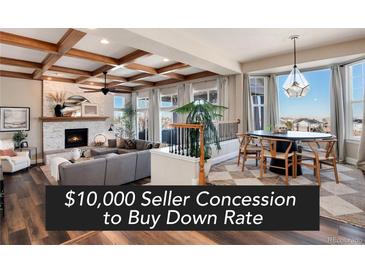 Bright living room boasts a coffered ceiling, fireplace, and an open floor plan that flows into the dining area at 27319 E Nova Cir, Aurora, CO 80016