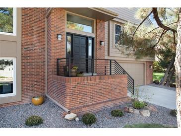 Charming brick front entrance with black door, minimalist railing, and beautiful landscaping detail at 8004 S Oneida Ct, Centennial, CO 80112