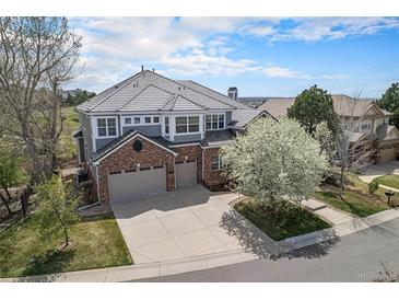 Stunning home exterior with brick accents, three car garage, and a lovely flowering tree at 22090 E Arbor Dr, Aurora, CO 80016