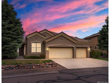 Charming single-story home boasts a three-car garage and beautifully landscaped front yard at sunset at 16631 Red Cliff Cir, Morrison, CO 80465
