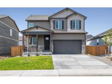 Two-story house with gray siding, stone accents, and a two-car garage at 9876 Ceylon Ct, Commerce City, CO 80022