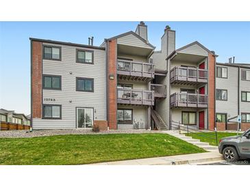 A multi-level condo building featuring grey siding, brick accents, and private balconies on each floor at 10785 W 63Rd Pl # 108, Arvada, CO 80004