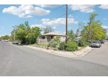 Charming single-story home featuring classic siding and a cozy front porch, surrounded by mature trees on a sunny day at 801 Hanover St, Aurora, CO 80010