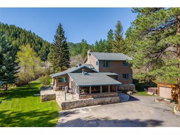 Charming home featuring a stone foundation, screened porch, and surrounded by lush greenery and mature trees at 11531 S Deer Creek Rd, Littleton, CO 80127