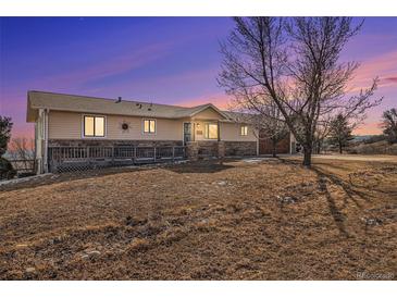 Charming home featuring covered porch, stone accents, garage and a mature tree at 5774 Sioux Dr, Sedalia, CO 80135