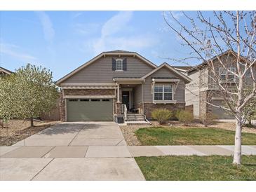 Charming single Gathering home featuring manicured lawn, grey trim, a stone facade, and a two car garage at 6747 W Jewell Pl, Lakewood, CO 80227