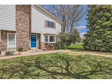 Charming townhome featuring a well-maintained lawn, stone accents, and a bright blue front door at 62 Newark St # C, Aurora, CO 80012