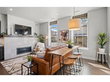 Modern living room showcasing a fireplace, stylish seating, and a unique bar-height table with stools at 4625 W 50Th Ave # 110, Denver, CO 80212