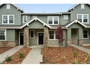 Inviting townhouse with stone accents, covered porch, manicured landscaping, and modern design at 17125 W 91St Ln, Arvada, CO 80007
