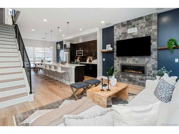 Open-concept living area boasts hardwood floors, modern kitchen, and a cozy fireplace feature at 1933 Grove St, Denver, CO 80204