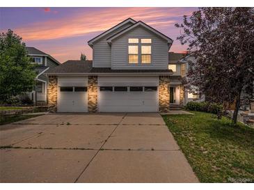 Two-story home with a three-car garage and brick accents, complemented by a well-manicured lawn and mature tree at 5755 S Zante Cir, Aurora, CO 80015