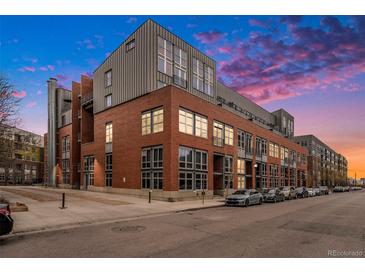 Modern building with red brick and large windows, complemented by a colorful sunset at 2955 Inca St # 2L, Denver, CO 80202