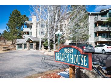 Bergen House condo complex with mature trees, covered entryway, and signage at 31819 Rocky Village Dr # 208, Evergreen, CO 80439