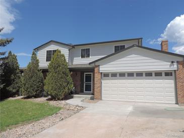Charming two-story home featuring a well-maintained lawn, mature trees, and a convenient two-car garage at 7753 W Plymouth S Pl, Littleton, CO 80128
