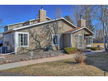 Charming home featuring a stone chimney, well-kept landscaping, and walkway leading to the entrance at 8450 Everett Way # D, Arvada, CO 80005
