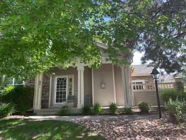 Charming single-story home featuring a welcoming front porch, stone accents, and mature trees at 601 Clarendon Loop, Castle Pines, CO 80108